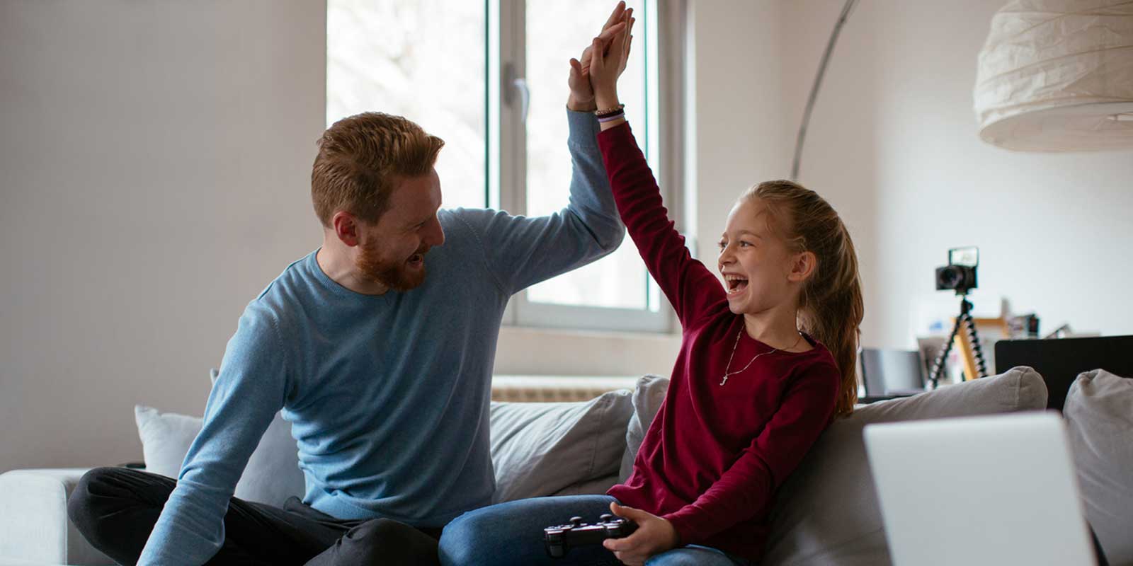 Daughter giving her dad a high five while playing a computer game