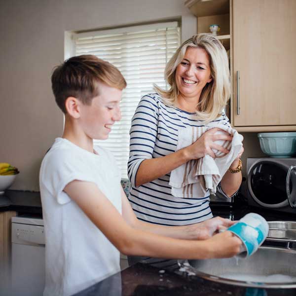 Mother and son talking while doing the washing up in the kitchen