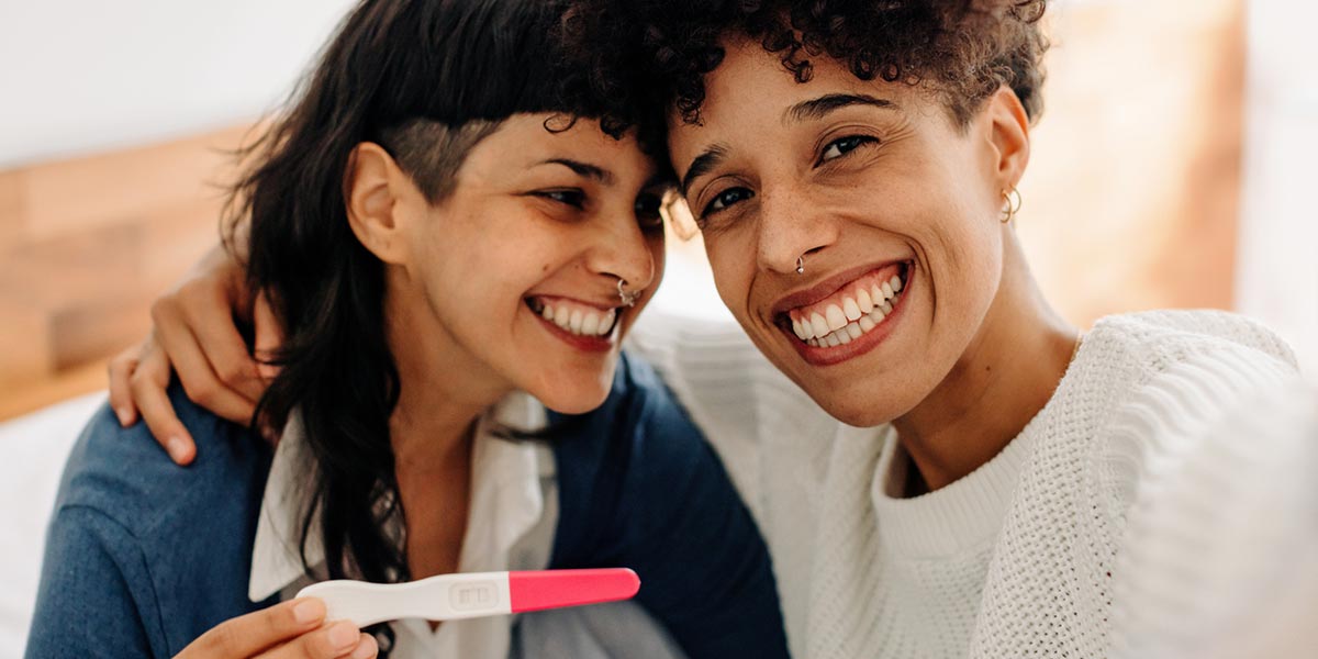 Same sex couple smiling at the results of a pregnancy test