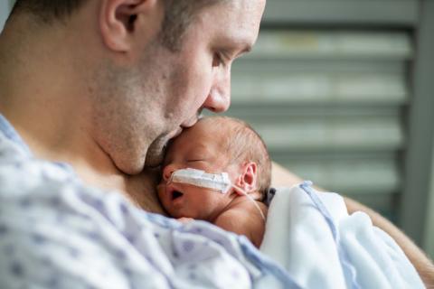 Dad holding premature baby next to his skin.