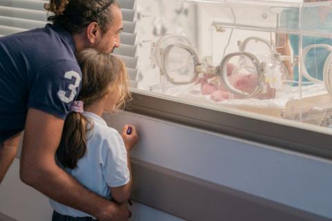 Dad and daughter visiting a premature baby in a neonatal unit