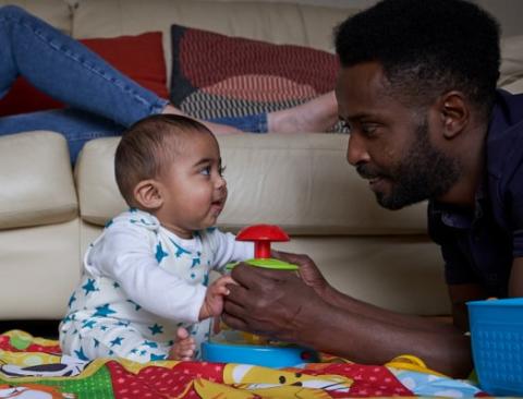Dad playing with baby on a play mat.