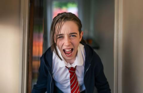 Girl wearing school uniform, screaming and looking unhappy.