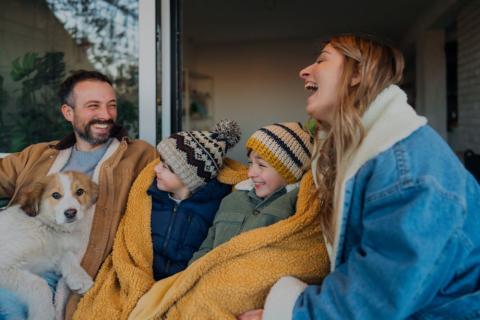 Family with dad, mum and two boys wrapped warm for winter, sitting with their dog.
