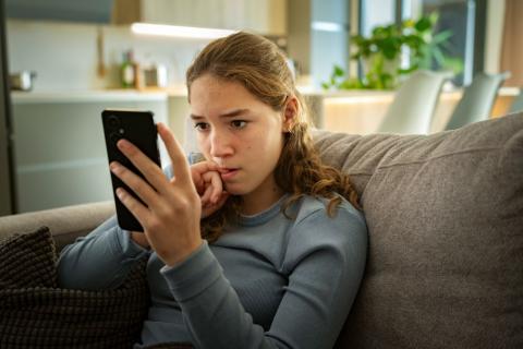 Anxious teenage girl looking at her phone.