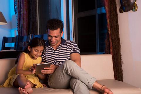 Dad and daughter looking at a tablet together.