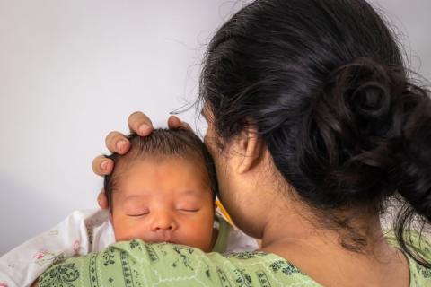 Mum holding a new baby against her shoulder.