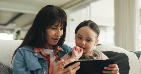 Mum and young daughter looking at a tablet together.