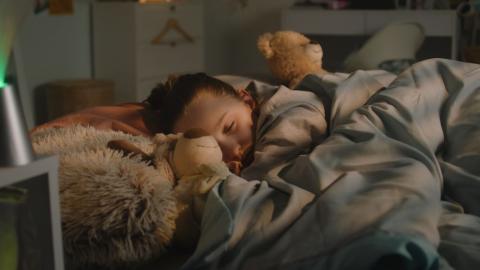 Girl asleep in bed with a teddy bear.