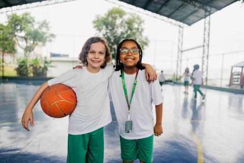Girls with their arms round each other, one carrying a basketball, the other wearing a Sunflower lanyard.