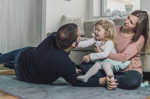 Happy family of dad, mum and toddler in their living room.