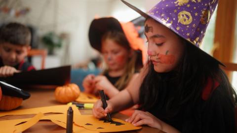 Family dressed up for Halloween, making Halloween crafts from paper.