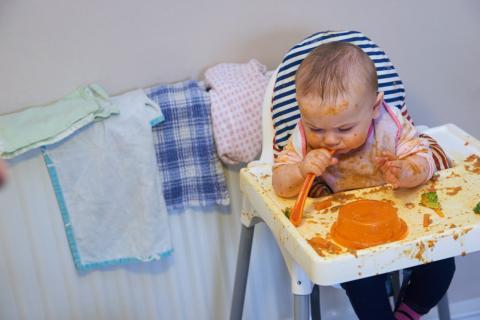 baby in highchair making a mess with their food