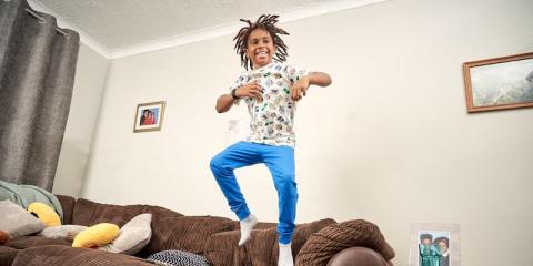 Image of a boy laughing and jumping on a sofa.