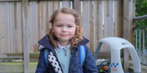 Photo of a young girl standing out side in coat 