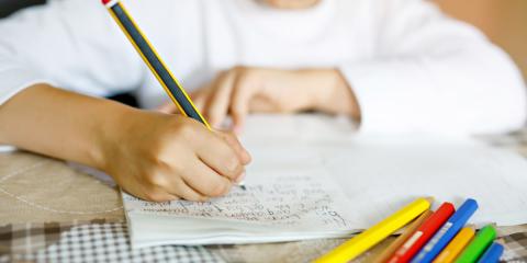 Photo of a child writing with coloured pencils 