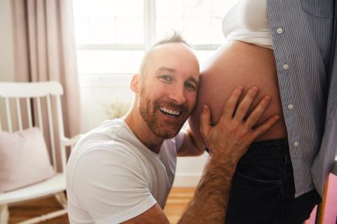 Smiling dad holding his partner's bump