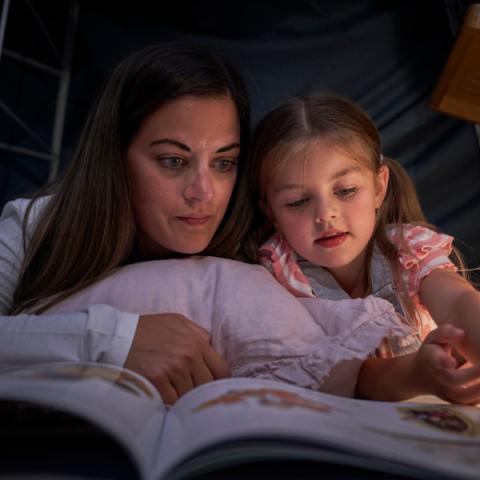 Photo of a girl reading with her mum
