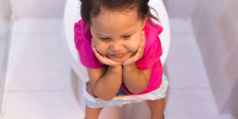 Image of a smiling toddler sitting on a toilet.