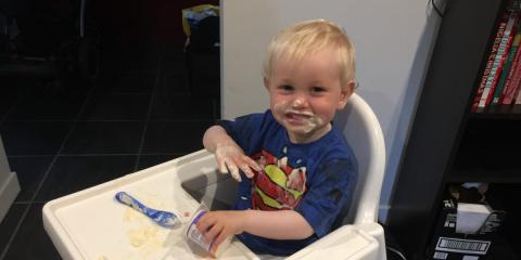 toddler sitting in a highchair eating yogurt