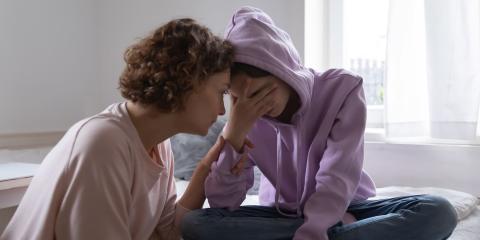 A worried mother comforting her sad teenage daughter