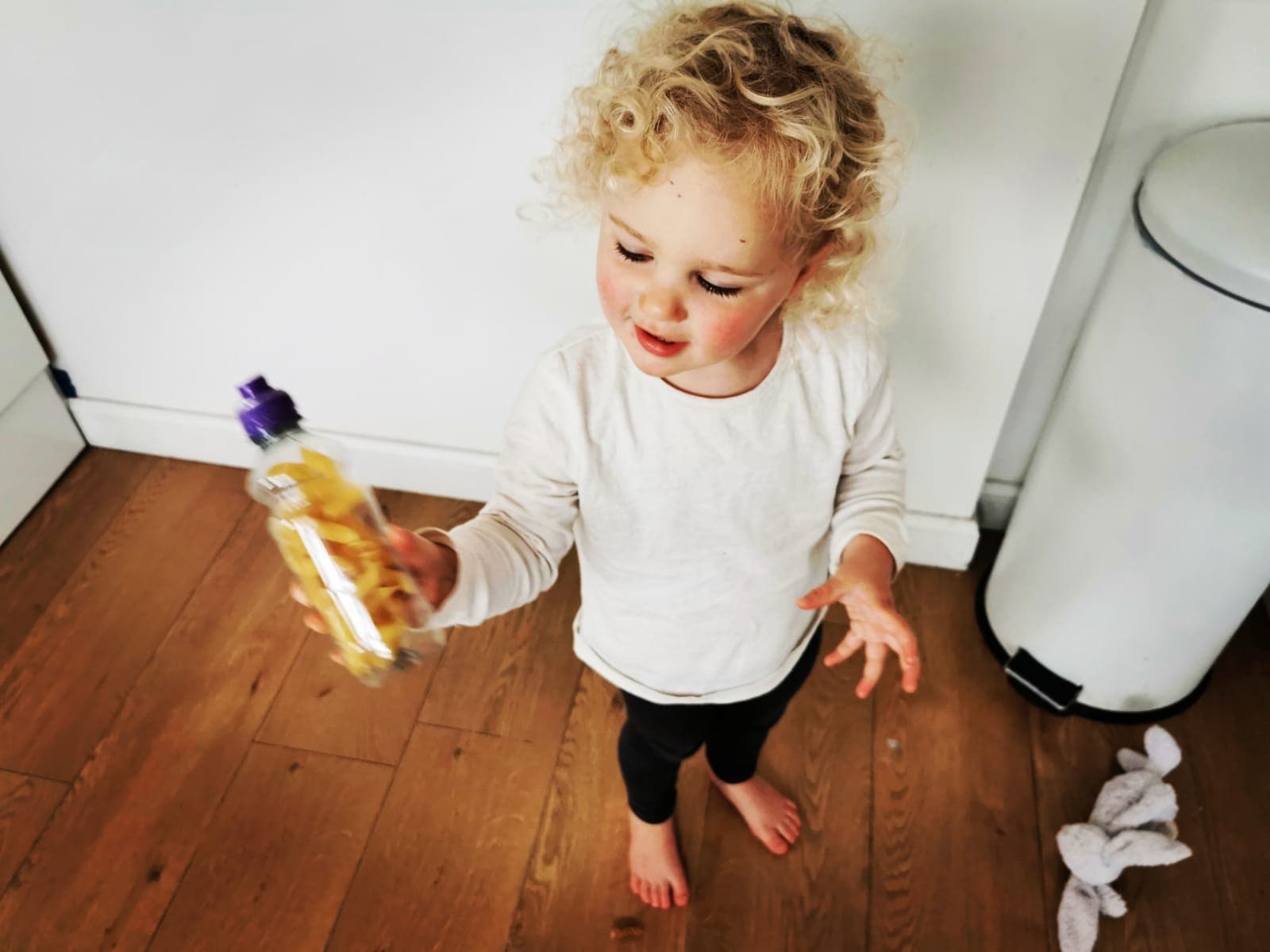 Image of a toddler smiling and holding a bottle.