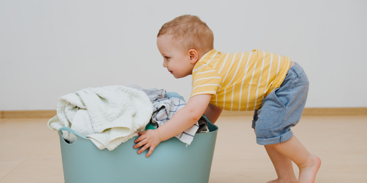 Photo of a toddler pushing a laundry basket