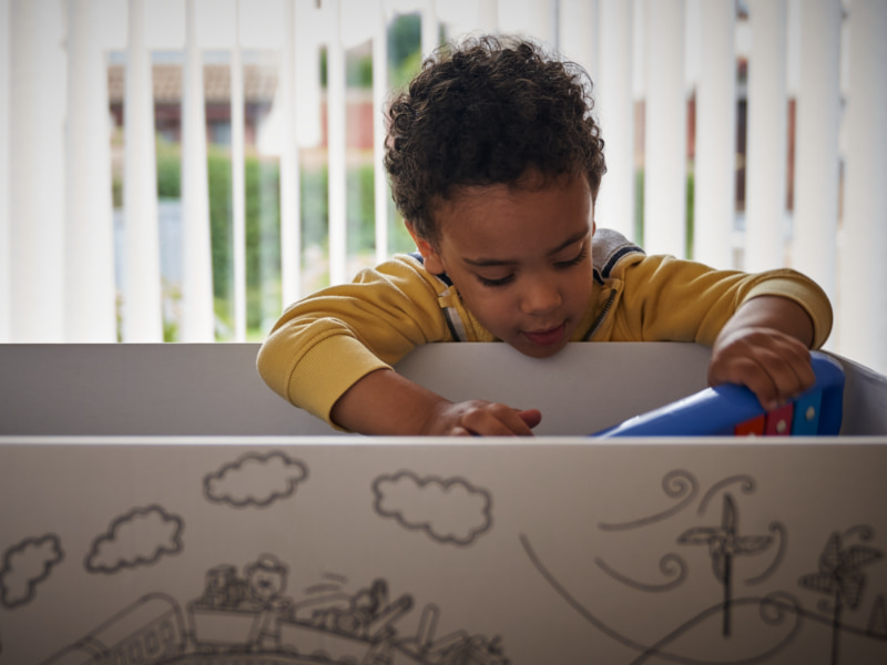 Image of a toddler putting a toy in a toy box.